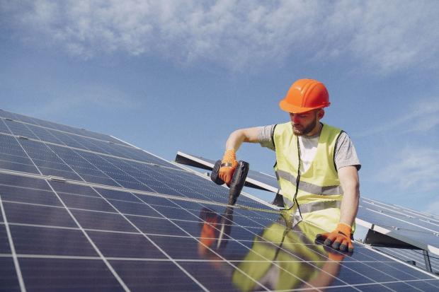Green Skills photo - a man on a roof drilling in a solar panel
